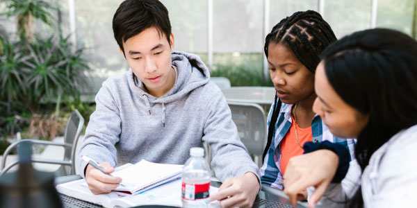 tres estudiantes miran apuntes de clase